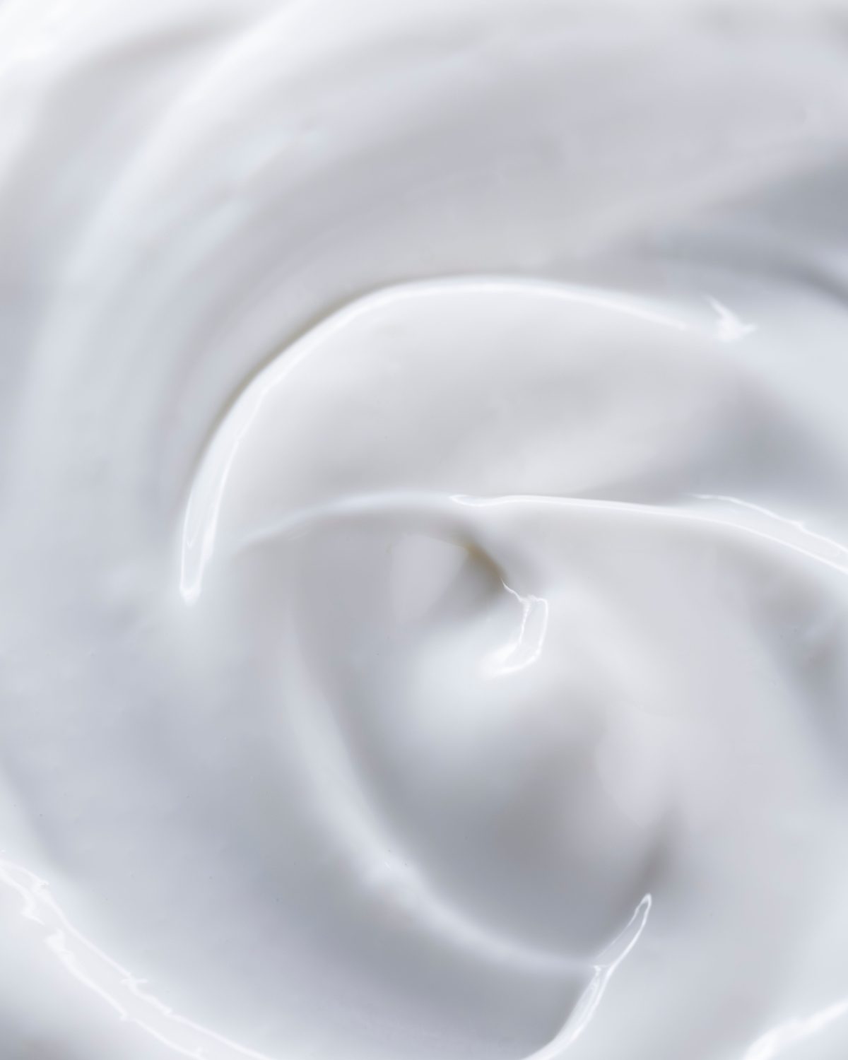 A close-up macro of white cream swirled into soft, glossy peaks.